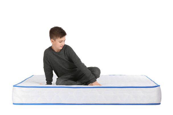 Roztomilý malý chlapec sedí na matraci proti bílému pozadí - Fotografie, Obrázek