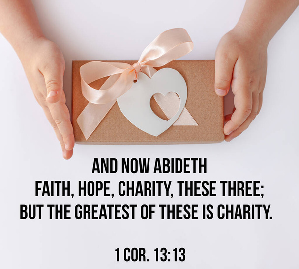 Bible quotes for believers. Inspirational Christian thoughts verse. Child's hands hold gift box. Love, people care kids donations charity, grace support welfare concept. Giving tuesday greeting card. - Photo, Image