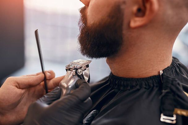 Barber grooming beard of modern client - Foto, afbeelding