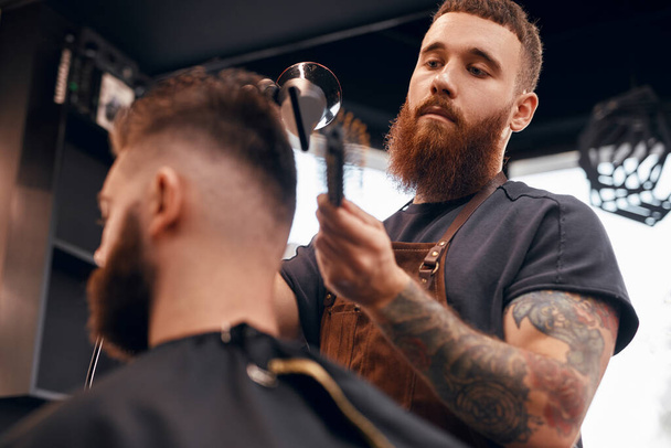 Trendy barber grooming male client in salon - Φωτογραφία, εικόνα