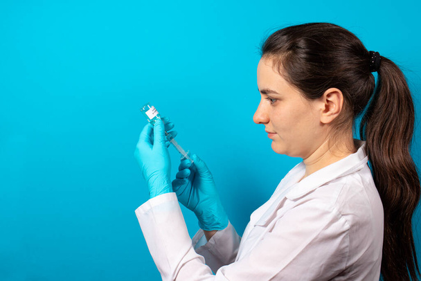 Un médecin ou un technicien de laboratoire tient un flacon avec un vaccin contre l'hépatite B à la main. Avec une place pour le texte sur un fond bleu - Photo, image