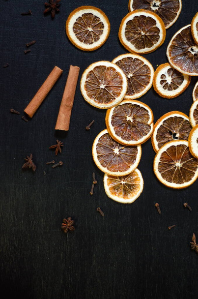 Set for mulled wine on a black background, scattered dry oranges, cinnamon, cloves, star anise, with copyspace - Φωτογραφία, εικόνα