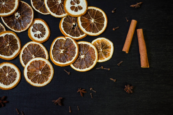 Set for mulled wine on a black background, scattered dry oranges, cinnamon, cloves, star anise, with copyspace - Foto, imagen