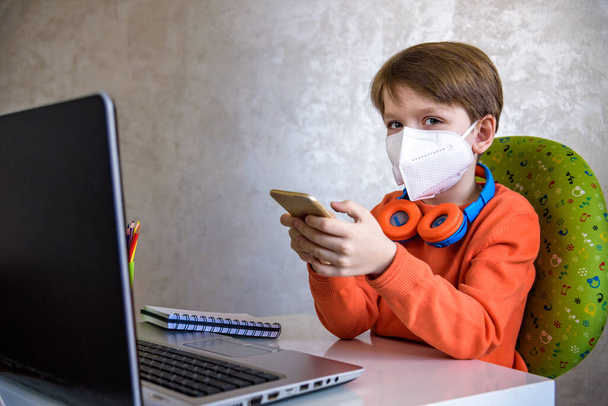Coronavirus Outbreak. Lockdown and school closures. School boy with face mask watching online education classes feeling bored and depressed at home. COVID-19 pandemic forces children online learning. - Foto, Bild