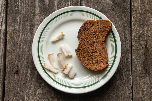 zwart sneetje brood met spek op een bord op een houten tafel voor de lunch - Foto, afbeelding