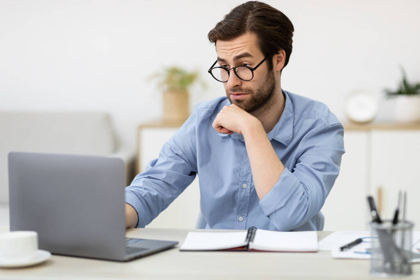 Verrast Business Guy op zoek naar laptop zitten in Office - Foto, afbeelding