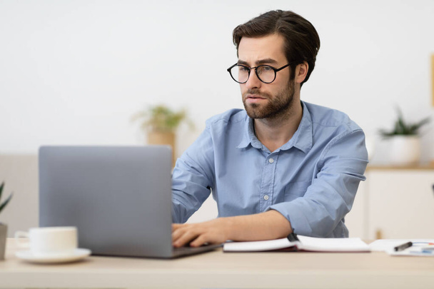 Podnikatel zamračený pracuje na notebooku s obtížným úkolem na pracovišti - Fotografie, Obrázek