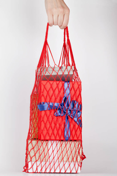 mão mulher segurando saco de compras eco-friendly reutilizável com caixas de presente no fundo branco.  - Foto, Imagem