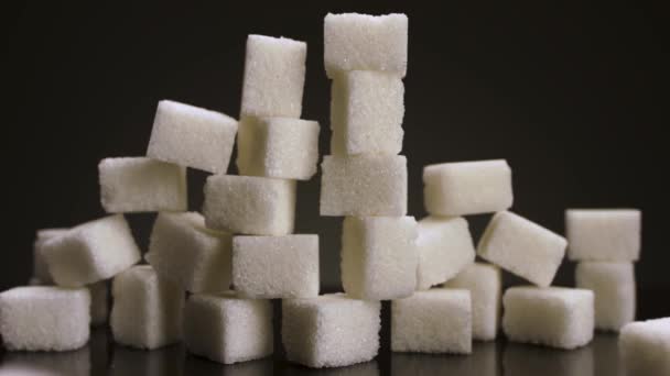 Cubos de cana-de-açúcar isolados sobre fundo preto. Imagens de stock. Close up de pirâmide feita de cubos brancos, conceito de doces e confeitaria. - Filmagem, Vídeo