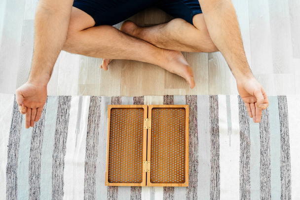 Vista cortada do homem exercitando ioga meditando e sentado no chão perto sadhu bordo - Foto, Imagem