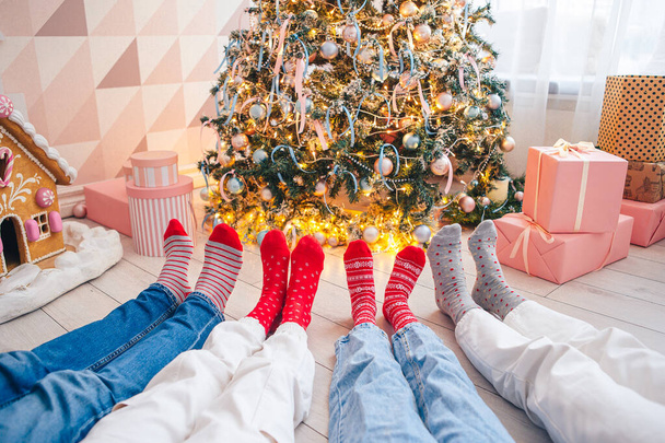Закрыть фотографию семейных ног в шерстяных носках у рождественской елки - Фото, изображение