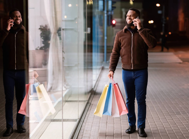 携帯電話で話す黒人男性ショッピングバッグを保持 - 写真・画像