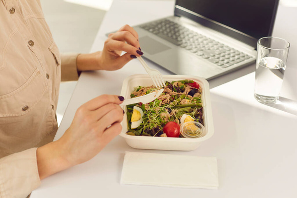 Hands of woman office worker eating healthy meal delivered by food delivery service - 写真・画像