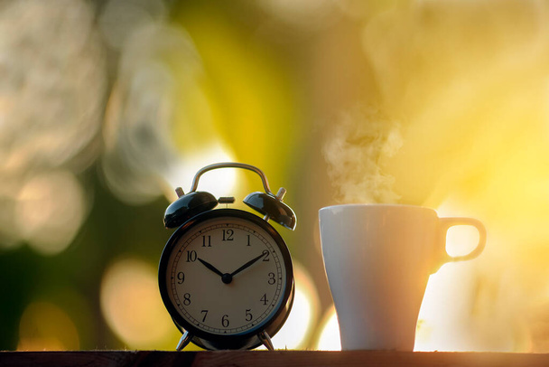 ブラック目覚まし時計と朝のコーヒーカップ - 写真・画像