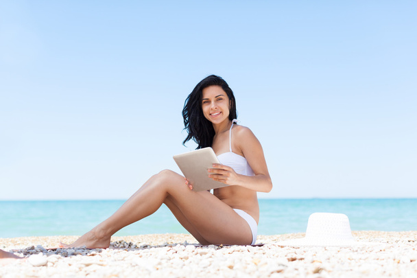 vrouw die tablet pc gebruikt op strand - Foto, afbeelding