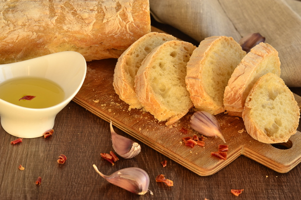 φρέσκο ψωμί - ciabatta, τσίλι και σκόρδο σε παλιά ξύλινη σανίδα - Φωτογραφία, εικόνα