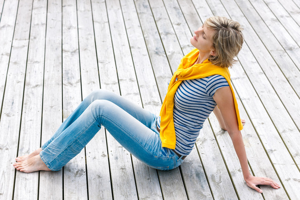 Woman sitting with closed eyes on wooden floor - Photo, image