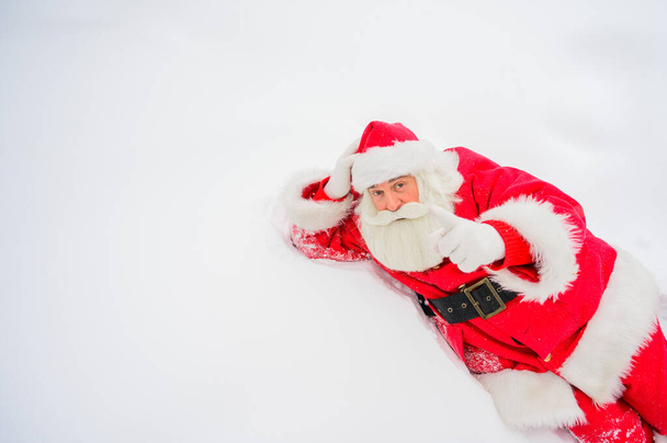 Happy santa claus lying in the snow and fooling around - Fotoğraf, Görsel