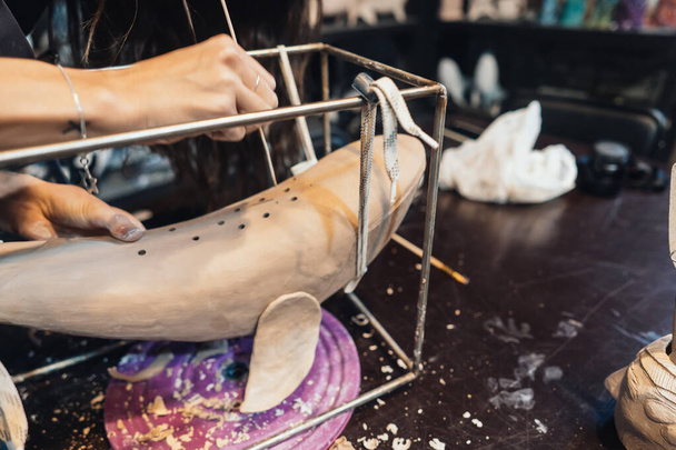 Detailní záběr ženských rukou jemně manipulujících s hliněnou velrybou v dílně. - Fotografie, Obrázek