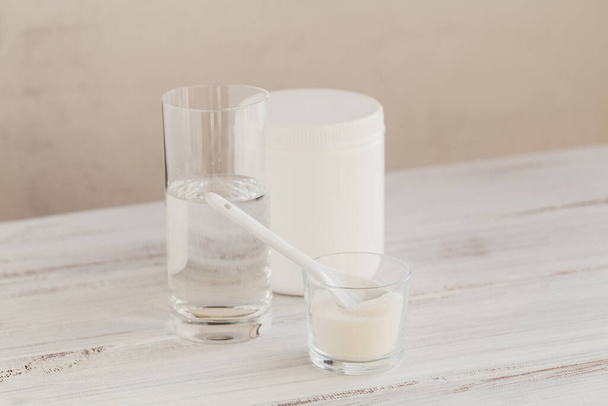 Hydrolyzed marine sourced collagen peptides in glass bowl and water on a white wooden background. Daily supplement concept. - Φωτογραφία, εικόνα
