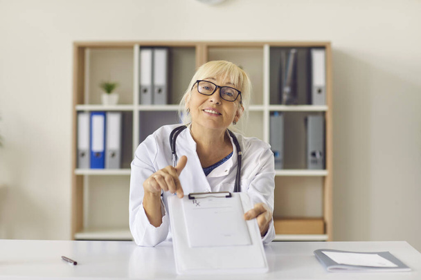 Friendly doctor pointing at medical prescription and explaining how to take medicine - 写真・画像
