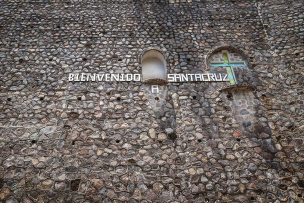 Письма на каменной стене у входа в деревню с надписью "Добро пожаловать в Санта-Крус" с религиозным крестом в Санта-Крус-Ла-Лагуна, Гватемала - Фото, изображение