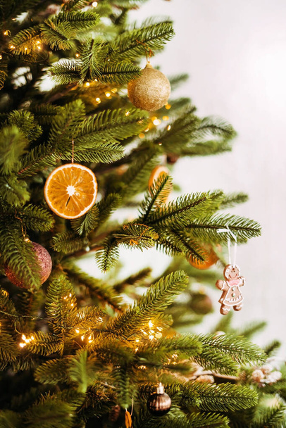 Vertical close-up of a Christmas tree with decorations toys, dried orange on a white background. - Valokuva, kuva