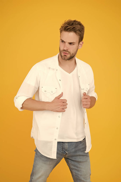 man in white shirt. Muscular man in jeans yellow background. fashion and people concept. Sexy and handsome. Confident young handsome man in jeans shirt. guy wearing jeans and white t-shirt - Photo, image