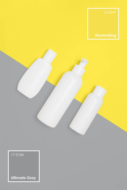 Cosmetic bottles on yellow and gray background - Photo, Image