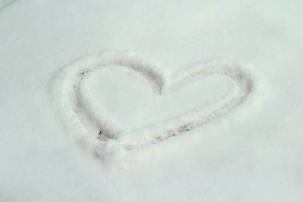 a heart drawn in the snow, winter white background. Concept of love, romance, wedding, valentine's day. Stock photo with empty space for text and design. - Foto, Imagem