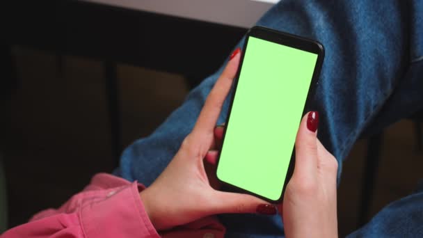 Chiudi le mani delle donne che tengono lo smartphone con schermo verde cromakey mentre guardano contenuti o video a casa. Gadgets concetto di persone. - Filmati, video