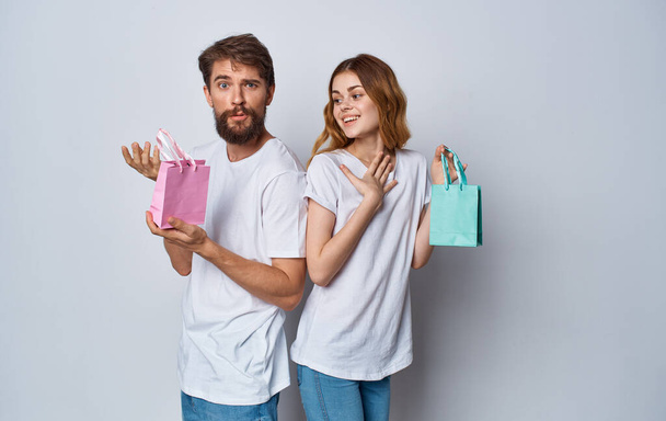 férfi és nő ajándék táskák álljon vissza egymáshoz szürke háttér - Fotó, kép