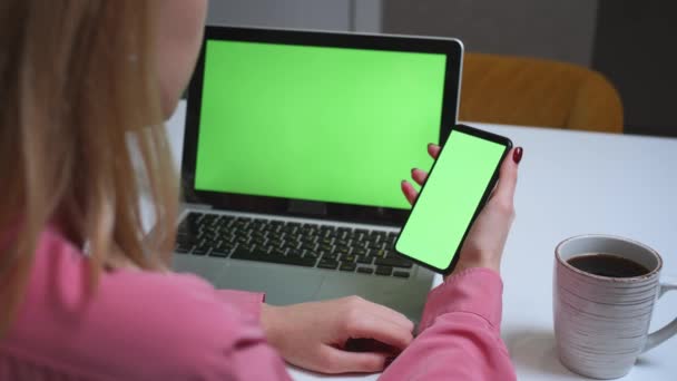 Κοντινό πλάνο γυναίκα χρησιμοποιώντας smartphone πράσινη οθόνη στο τραπέζι με φορητό υπολογιστή Chromakey. Κοντινό πλάνο των γυναικών χέρια κρατώντας κινητό τηλέφωνο swipping κύλιση πράσινη οθόνη.. - Πλάνα, βίντεο