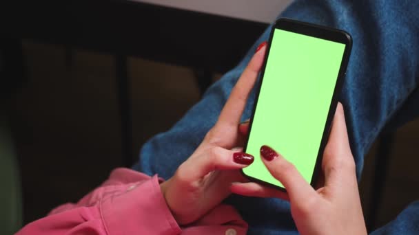 Feche as mãos da mulher segurando o smartphone de tela verde chromakey assistindo conteúdo, deslizando rolagem, escreve no telefone em casa. Gadgets conceito de pessoas. - Filmagem, Vídeo