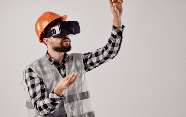 engenheiro civil em um capacete laranja e em óculos 3D em um fundo leve - Foto, Imagem