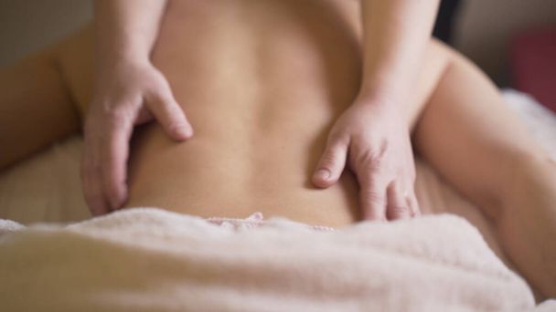 Suavizando los movimientos del masajista. Acción. Masaje de espalda relajante profesional en Spa. Salón de masaje ligero para la relajación y la recuperación - Foto, imagen