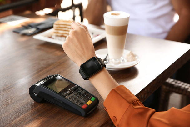Woman making payment with smart watch in cafe, closeup - Zdjęcie, obraz