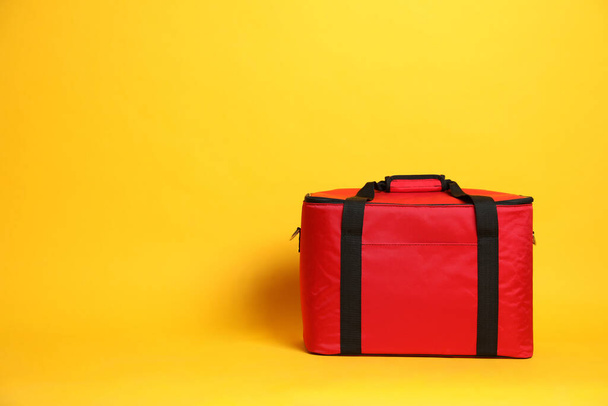 Modern red thermo bag on yellow background. Space for text - Zdjęcie, obraz