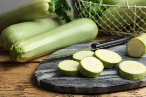 Sliced zucchini and grey marble board on wooden table, closeup - Foto, Imagem