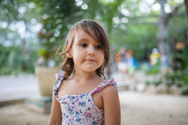 Adorable petite fille portant une robe fleurie avec un fond flou - Photo, image