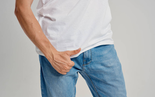 a man in jeans and a t-shirt shows a thumb up below the belt - Foto, Bild