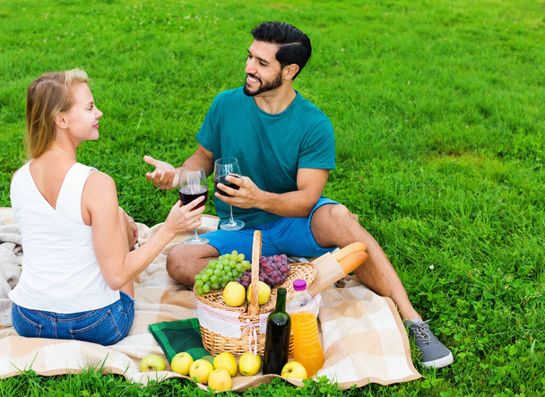 Couple are talking and drinking wine in time picnic outdoor - Фото, зображення