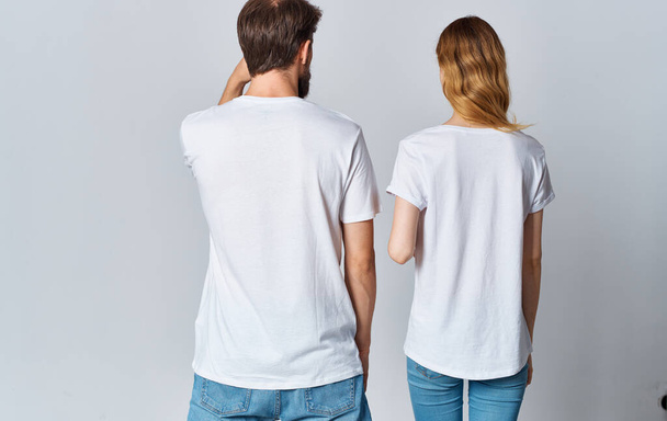 Een man en een vrouw in dezelfde T-shirts en jeans gebaren met hun handen, achteraanzicht - Foto, afbeelding