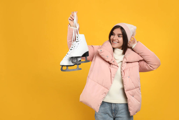 Emotional woman with ice skates on yellow background - Foto, afbeelding
