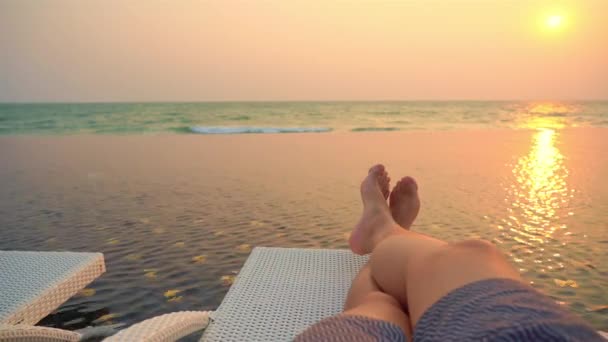 abgeschnittene Aufnahmen von Beinen eines Mannes, der sich an der Küste entspannt - Filmmaterial, Video