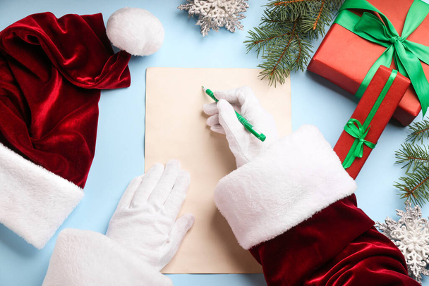 Top view of Santa writing letter at light blue table, closeup - Photo, Image