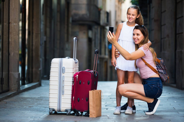 Woman with little daughter traveling together, taking selfie - 写真・画像