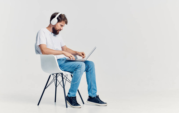 Muž sedí na židli před notebookem ve sluchátkách komunikační technologie izolované pozadí - Fotografie, Obrázek