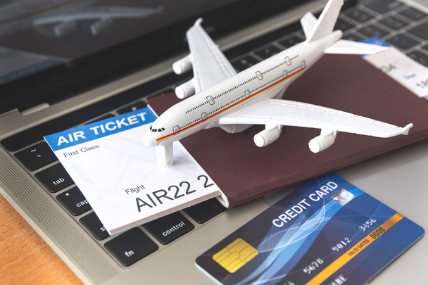 Billets d'avion et passeports près de l'ordinateur portable et de l'avion sur la table. Concept de réservation de billets en ligne - Photo, image