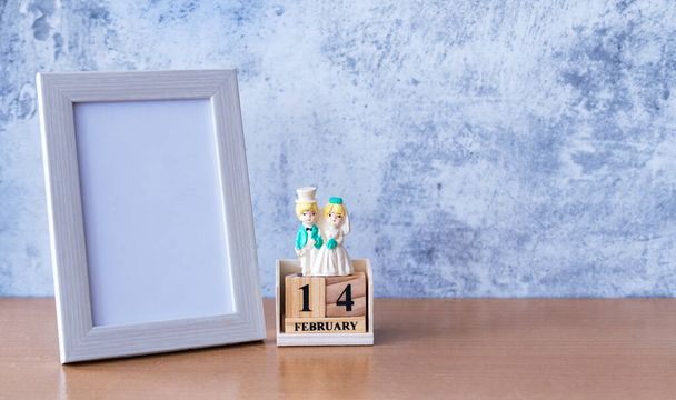 Картинная рамка и миниатюрная свадебная пара на столе. День Святого Валентина  - Фото, изображение